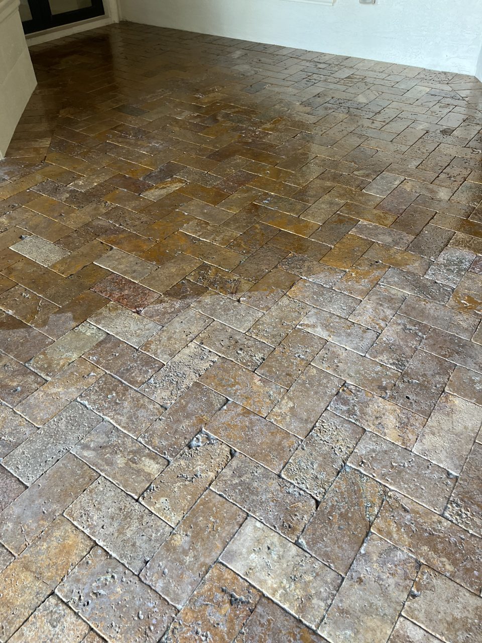 Travertine patio being sealed in South Florida with a wet-look finish bringing out the color