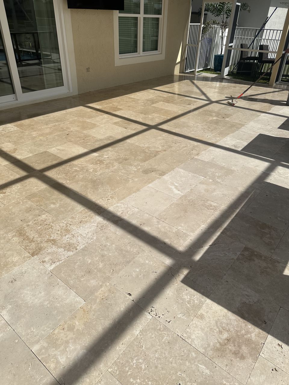 Travertine patio under a screen enclosure, cleaned and sealed in South Florida