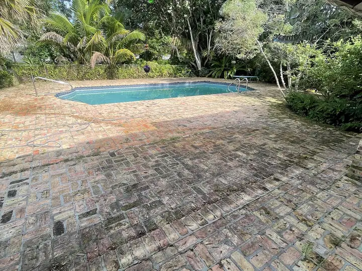 Brick paver pool deck darkened with mildew in South Florida — before