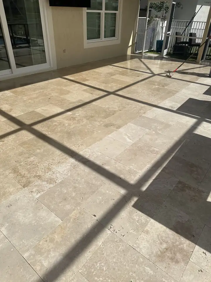 Travertine patio under a screen enclosure, cleaned and sealed in South Florida